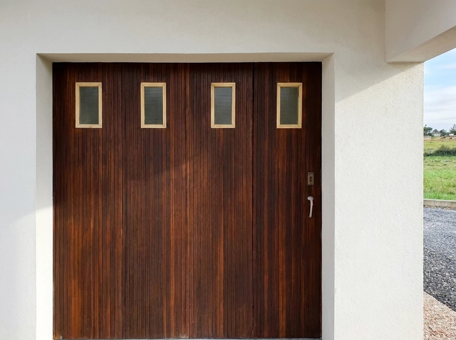 Porte de garage résidentielle blanche à panneaux surélevés avec quatre fenêtres rectangulaires à carreaux noirs